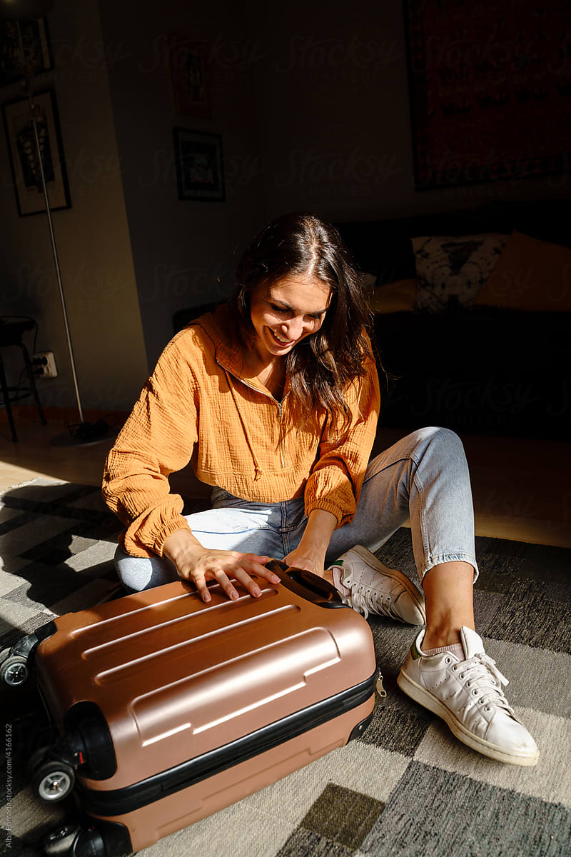 Woman closing suitcase at home