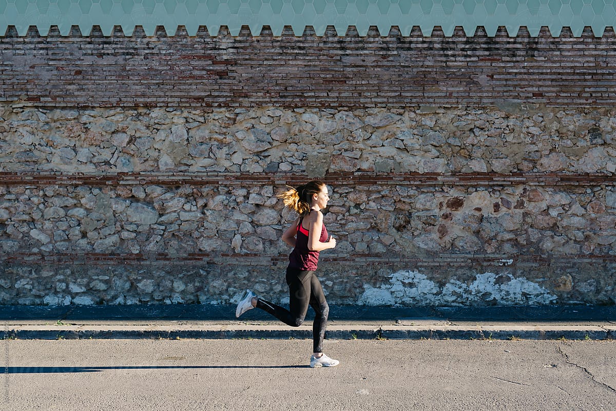 Woman running fast alongside wall