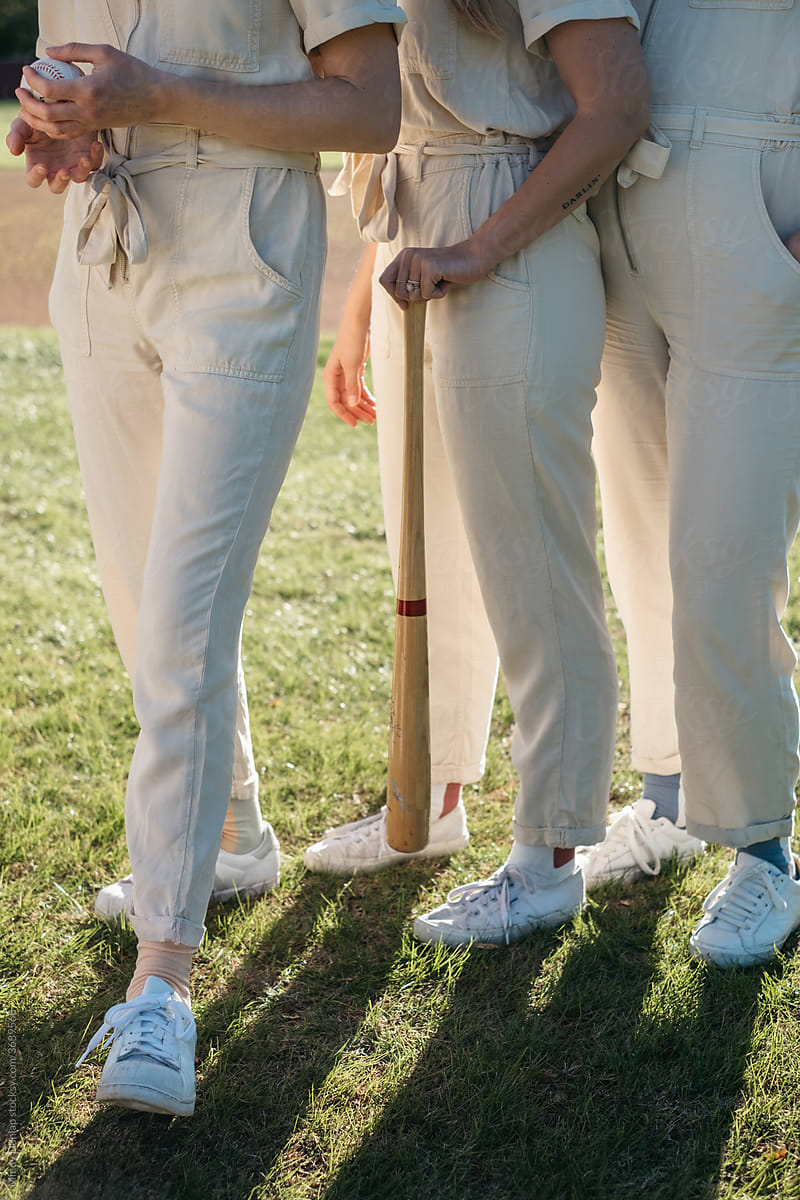 Young women\'s legs standing in formation on a baseball field