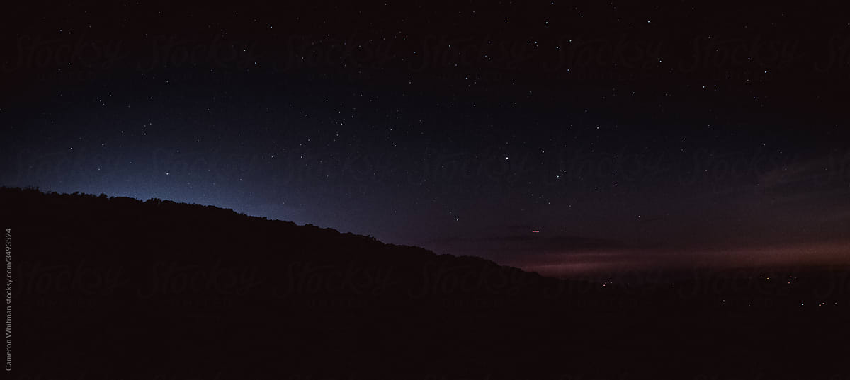 Light pollution creating a silhouette behind a mountain ridge