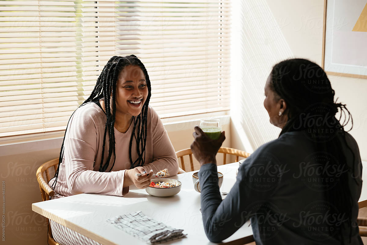Black daughter speaking with mother during breakfast