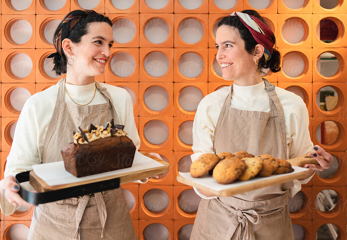 Smiling bakers with freshly baked cake and biscuit