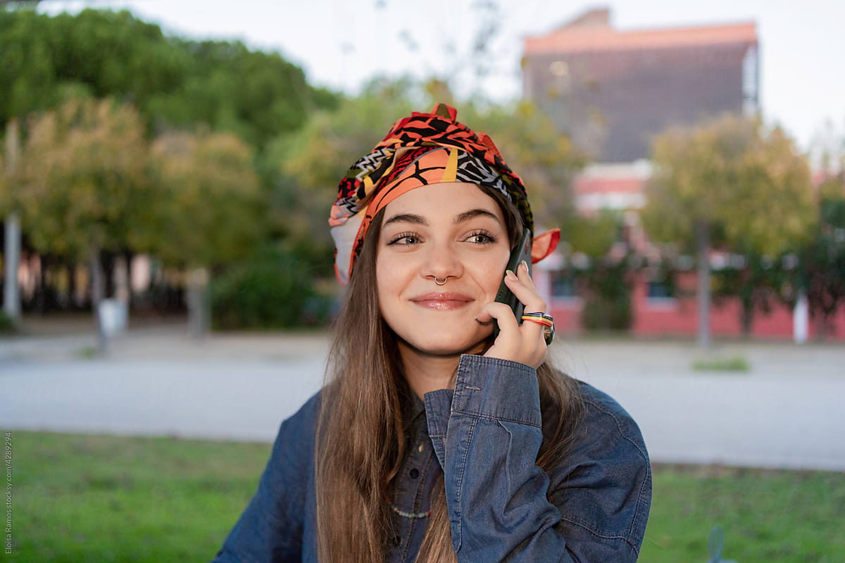 Cheerful woman talking by phone at university campus