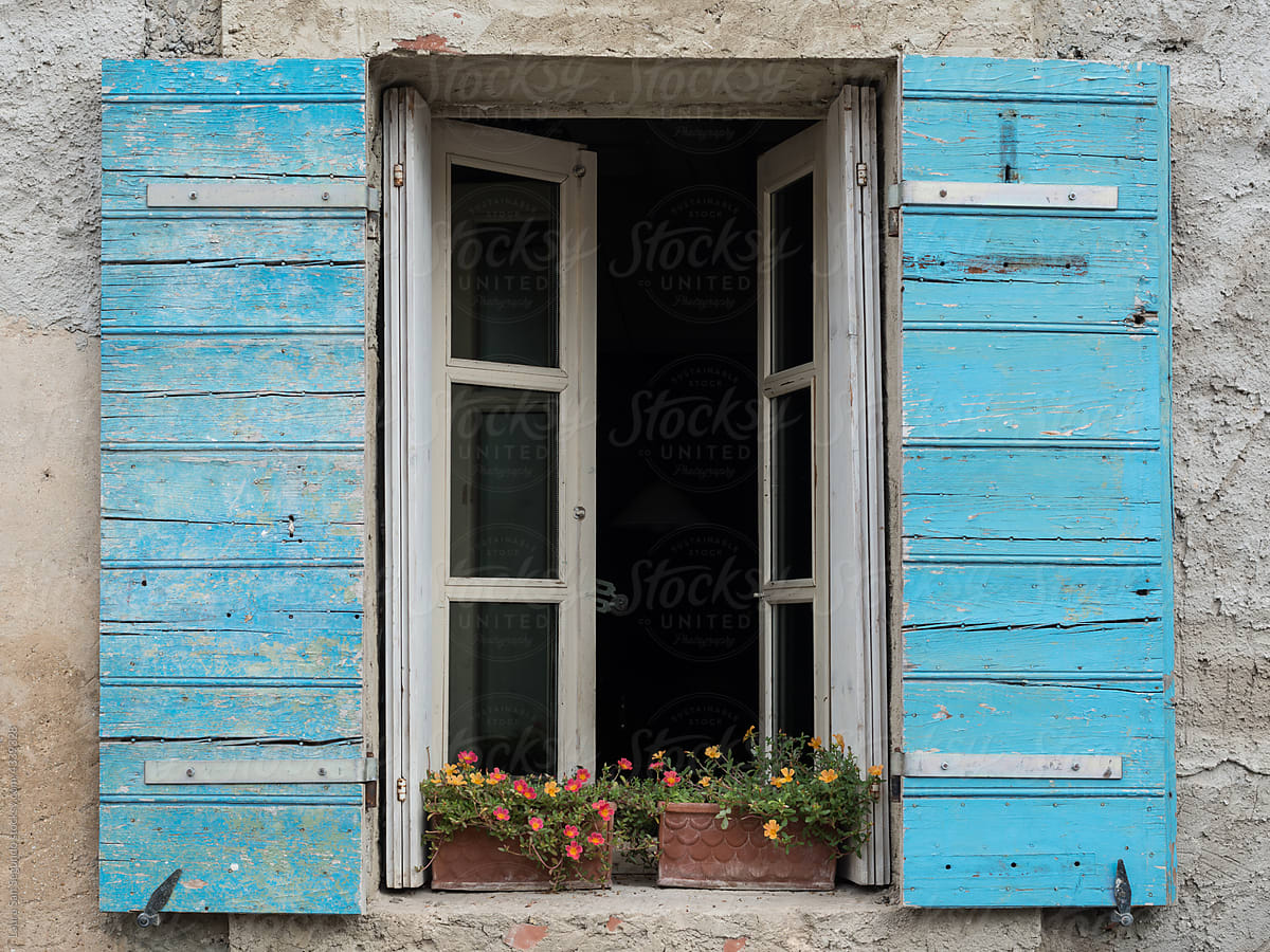 Window with blue wood shutters and flowers