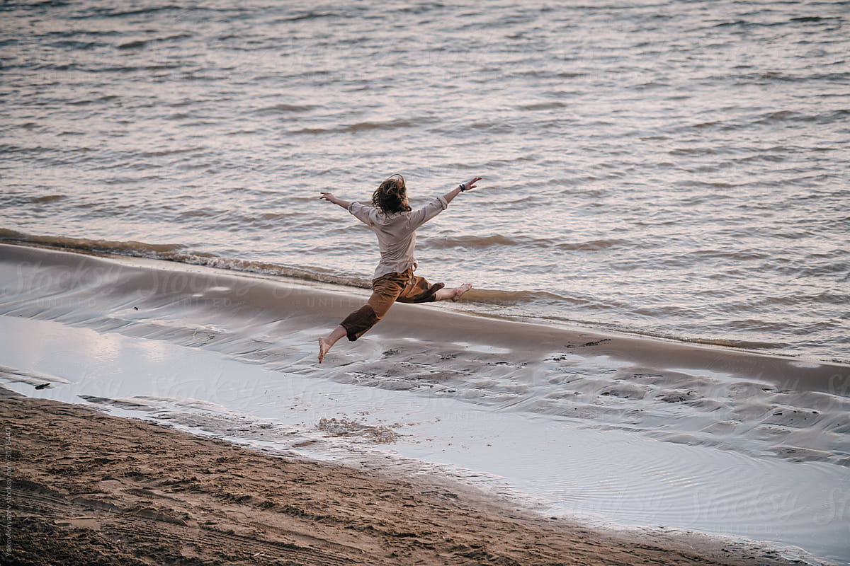 Professional dancer doing grand jete on the beach