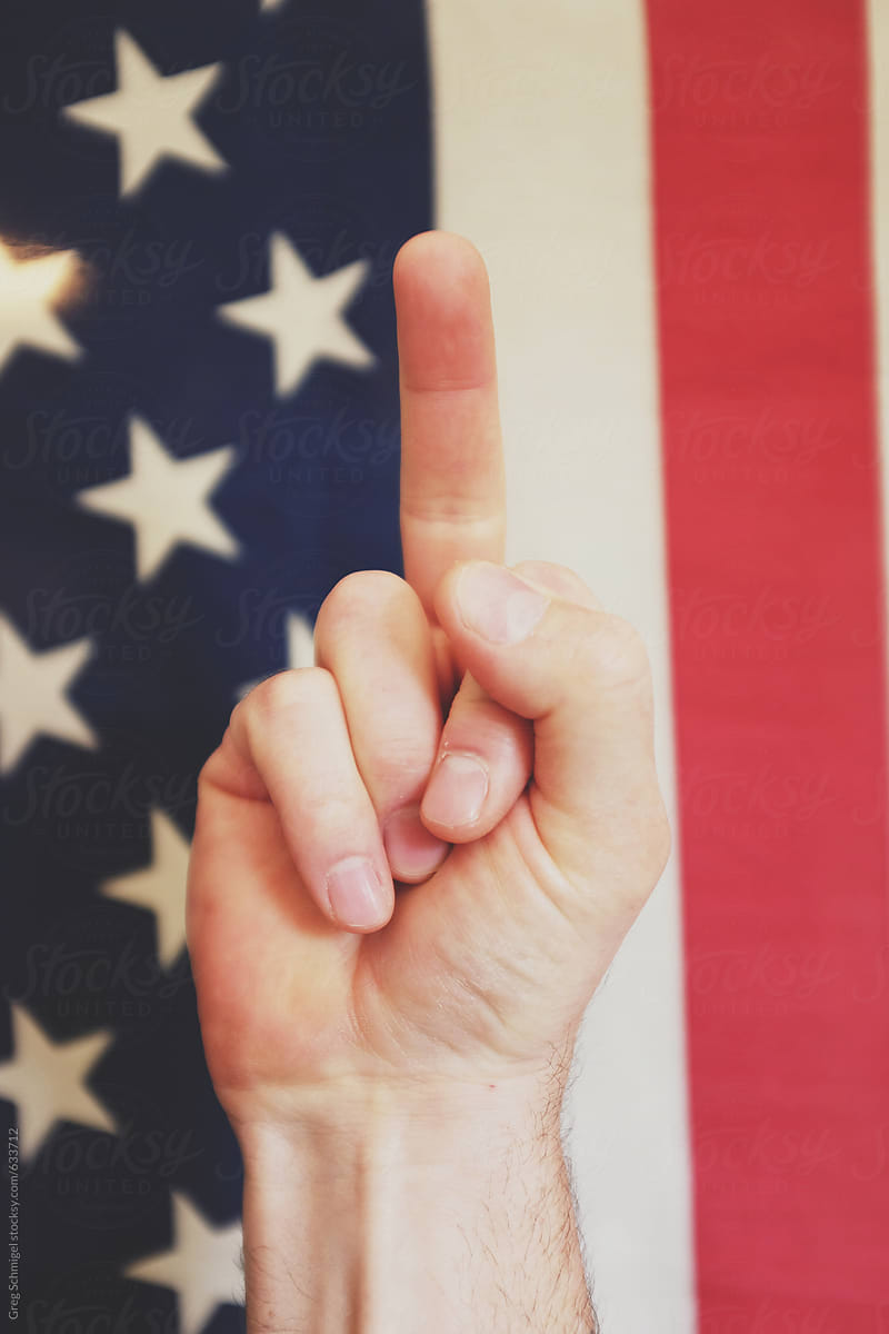 Fuck you hand and finger gestures in front of an old American Flag
