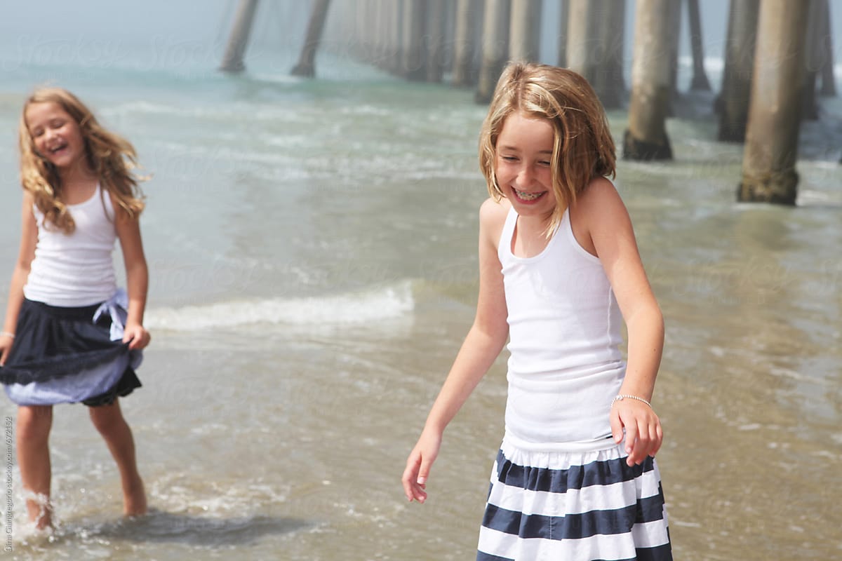 Two Girls Playing At The Beach By The Pier By Stocksy Contributor Dina Marie Giangregorio