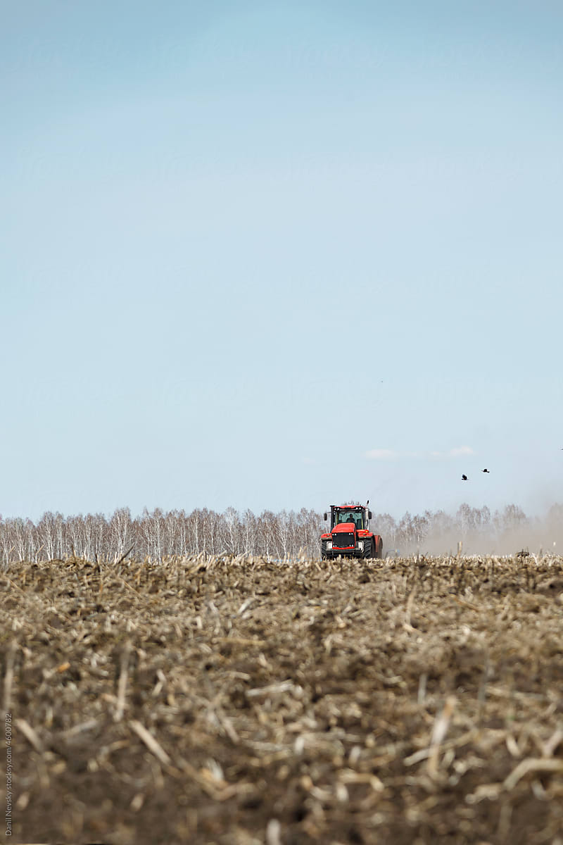 Tractor working in agricultural field under blue sky