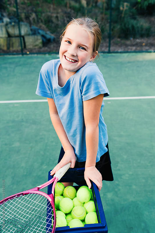 tween girl with tennic racket and a basket of balls