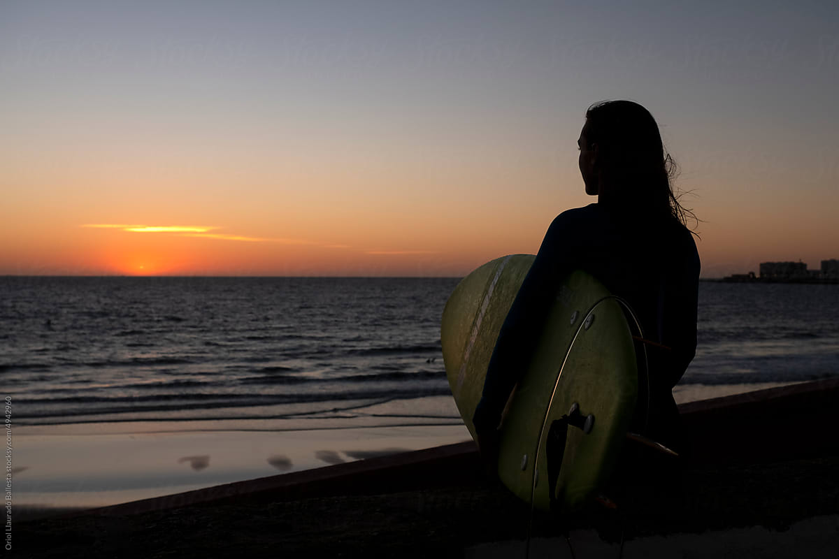 A surfer girl looking at a sunset