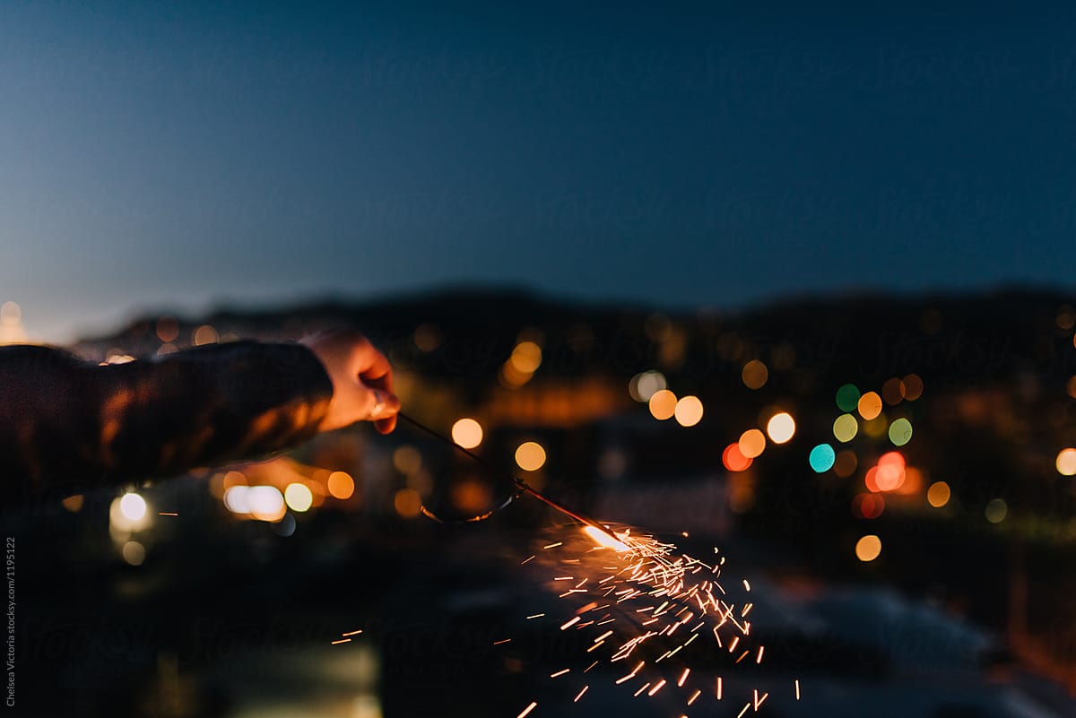 A woman holding a sparkler in the city