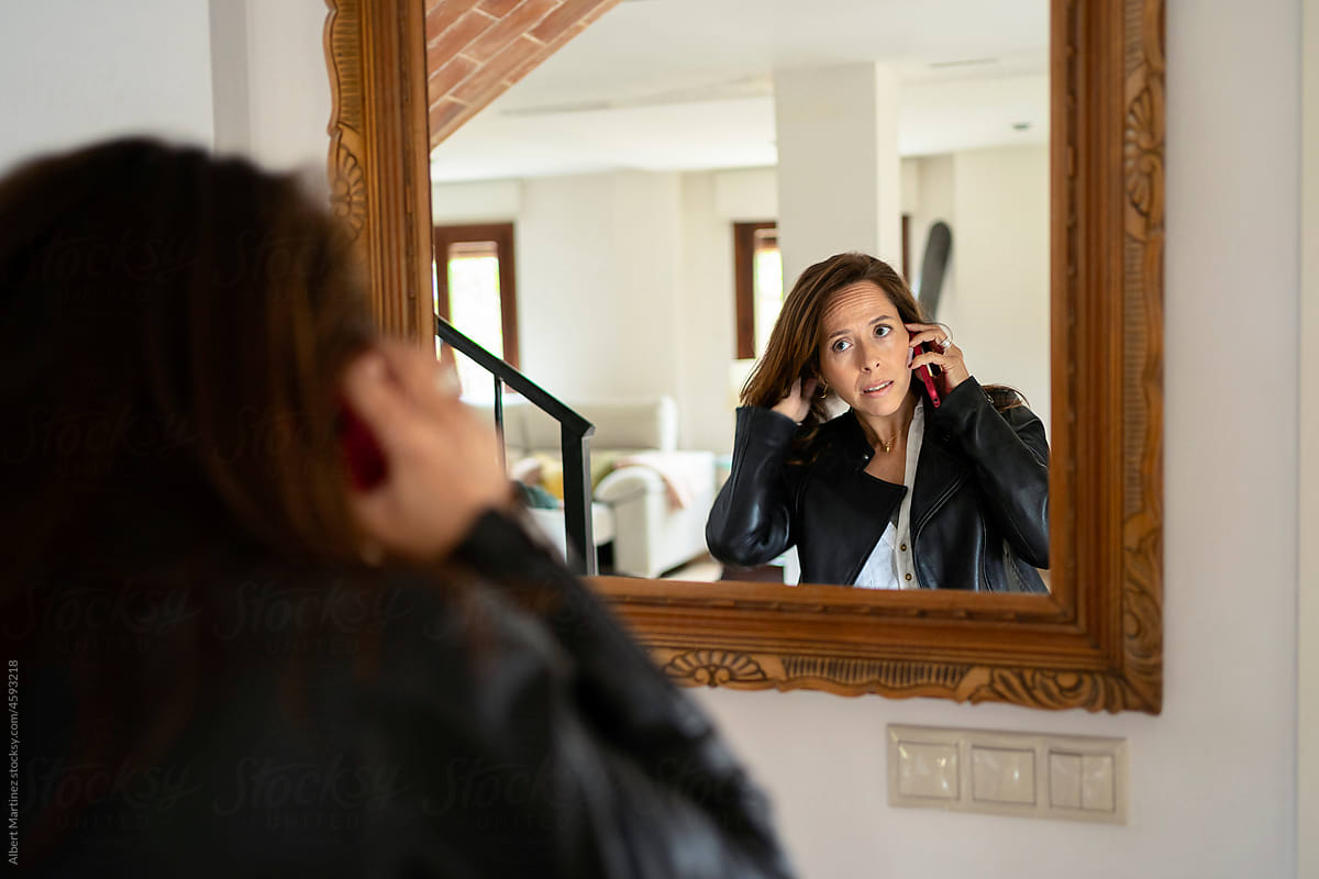 Woman talking on smartphone near mirror