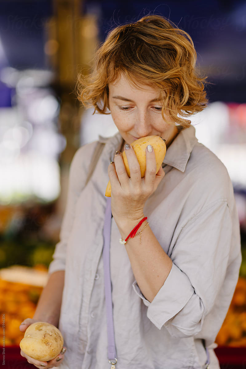 Woman smelling mango fruit in local market