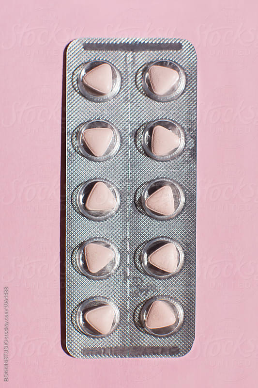 Pills in blister pack on pink background from above.