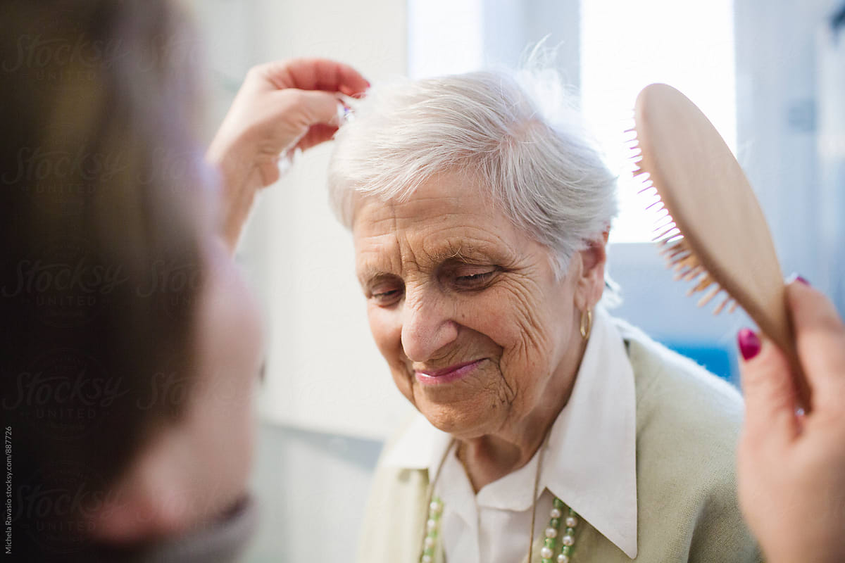 A caregiver brush the hair of an elderly lady