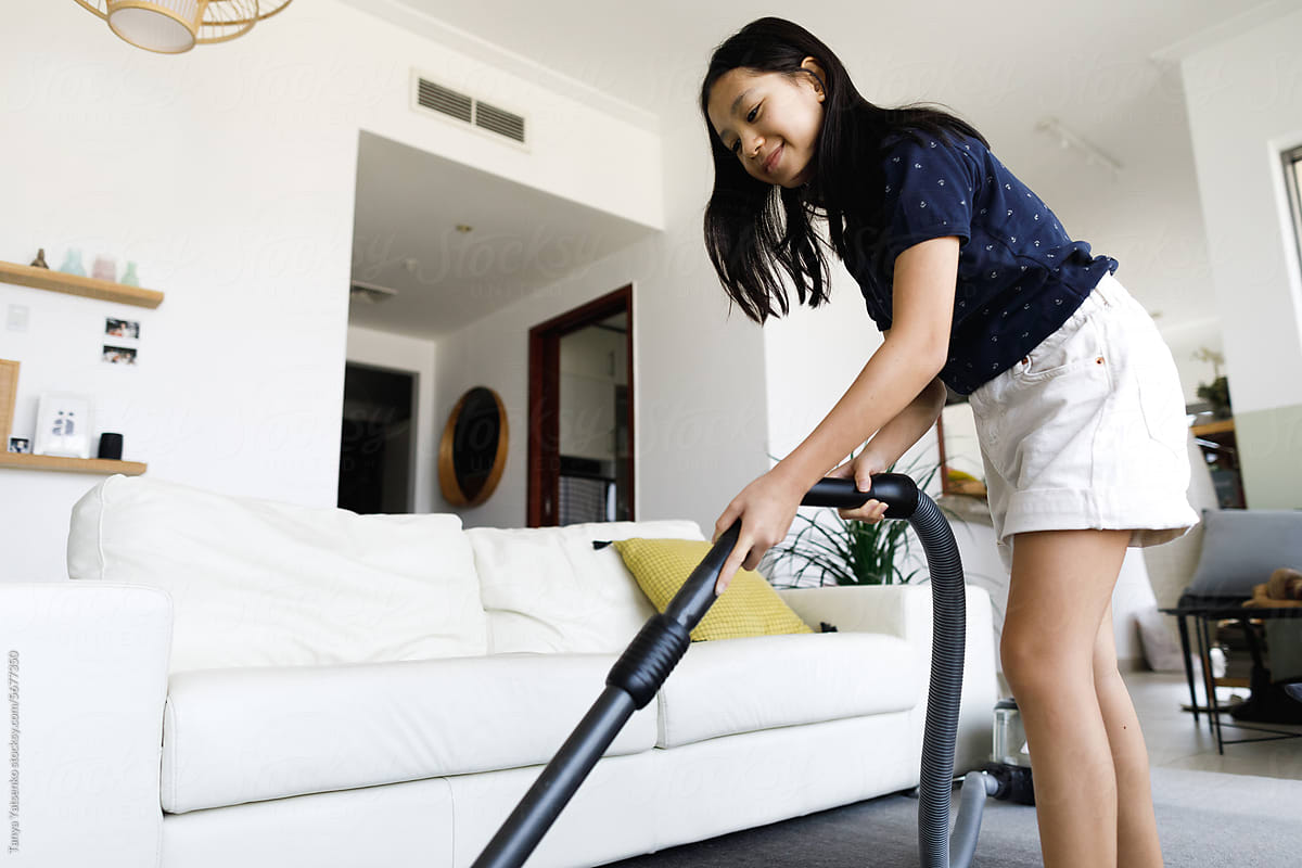 A girl vacuum-cleaning the carpet at home