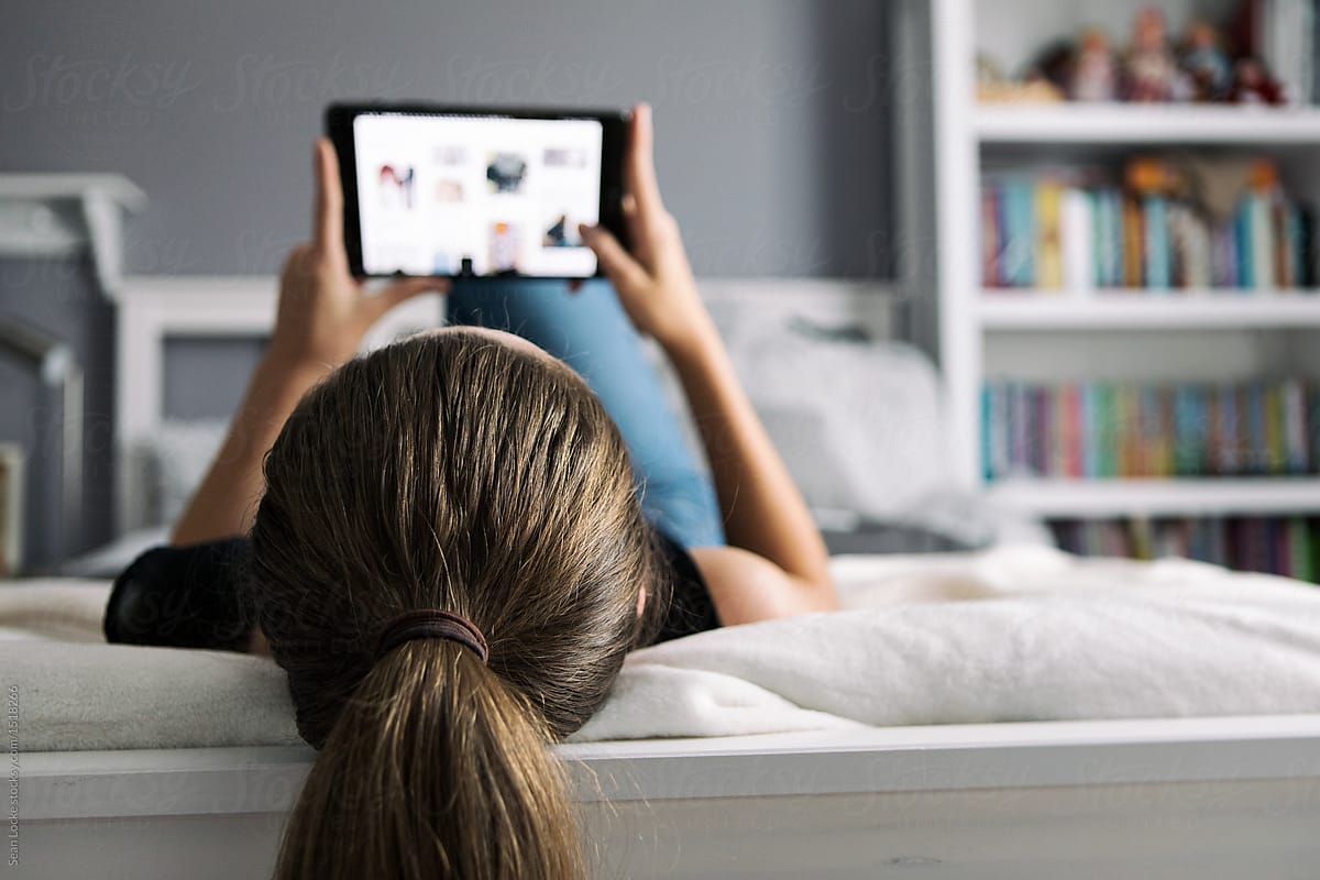 Teenager: Girl Relaxes In Bedroom Looking At Photo Website