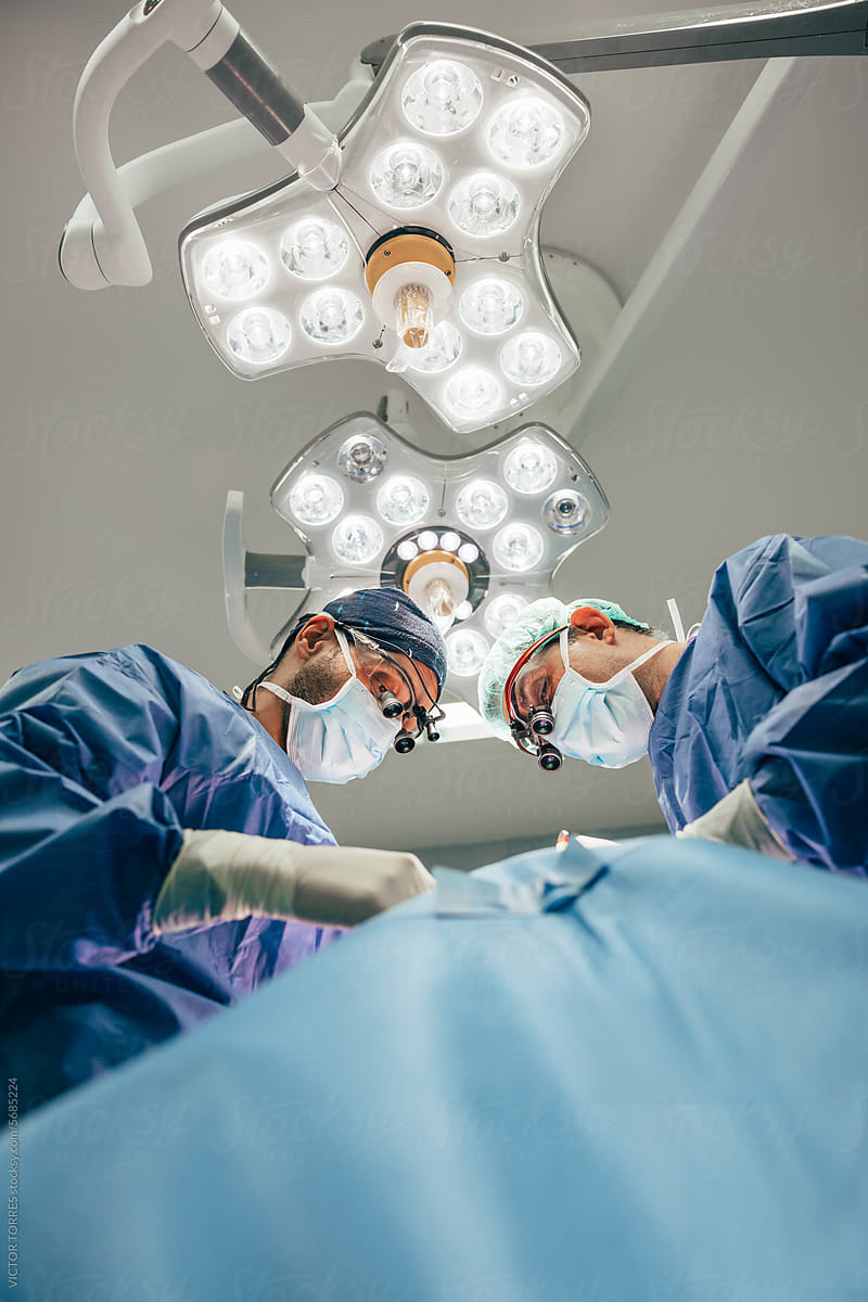 Male doctors performing thyroid surgery in operating room