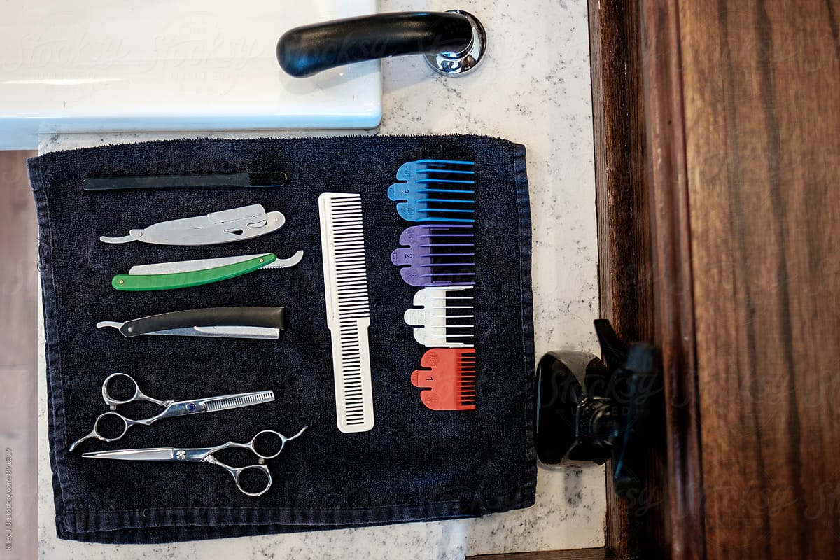 A barber\'s tools laid out on a towel next to a sink.