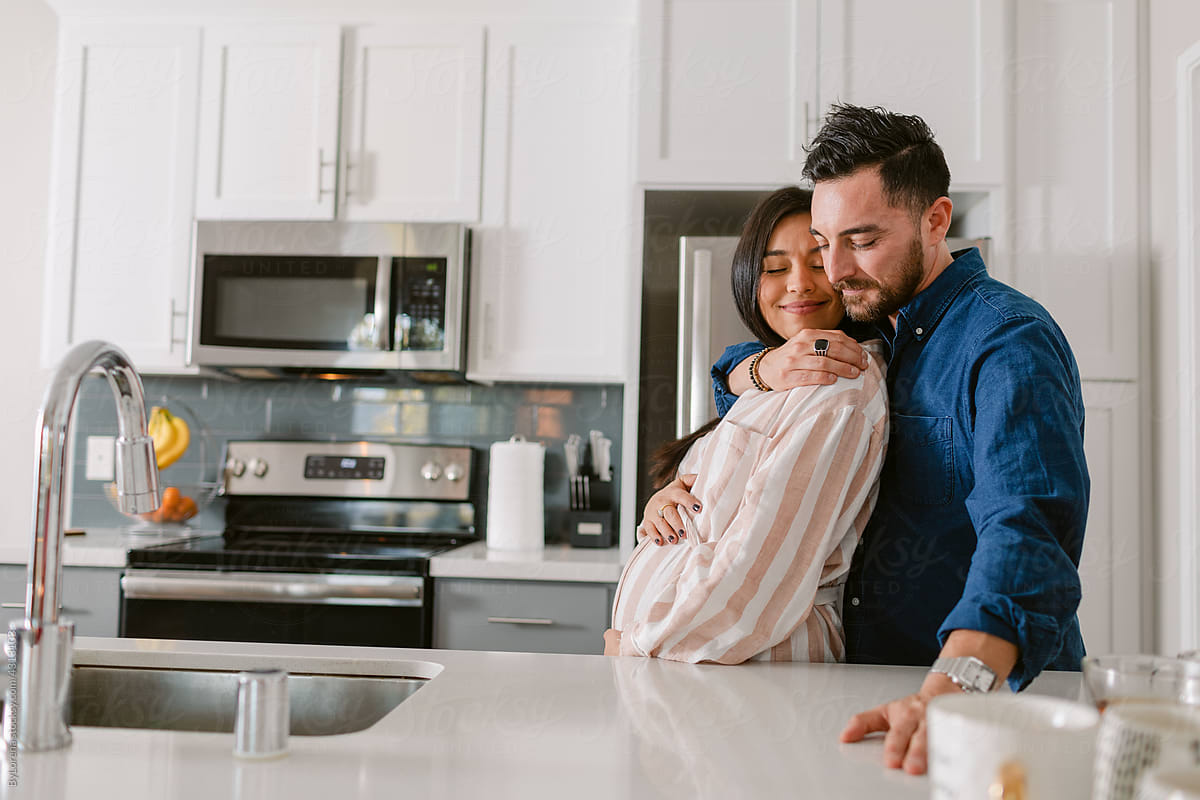 Husband hugging his pregnant wife in kitchen
