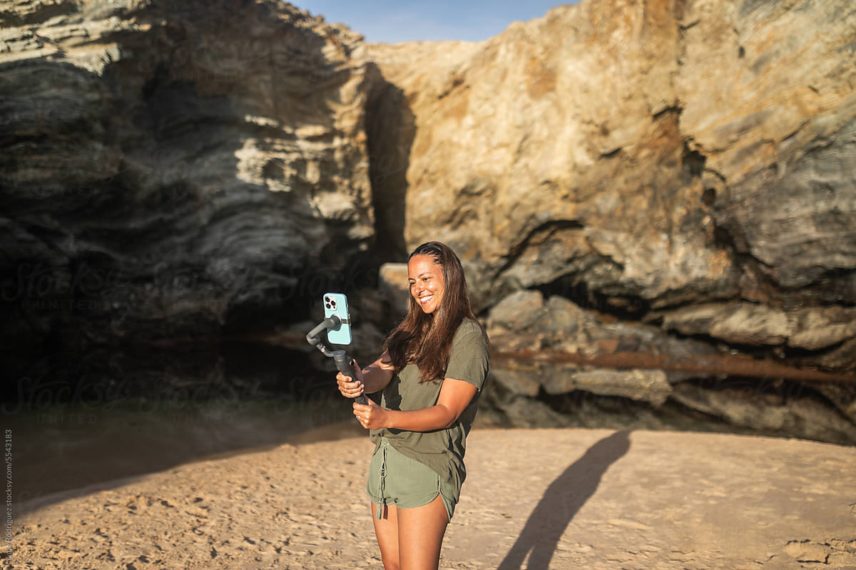 videographer woman using mobile phone with gimbal in nature