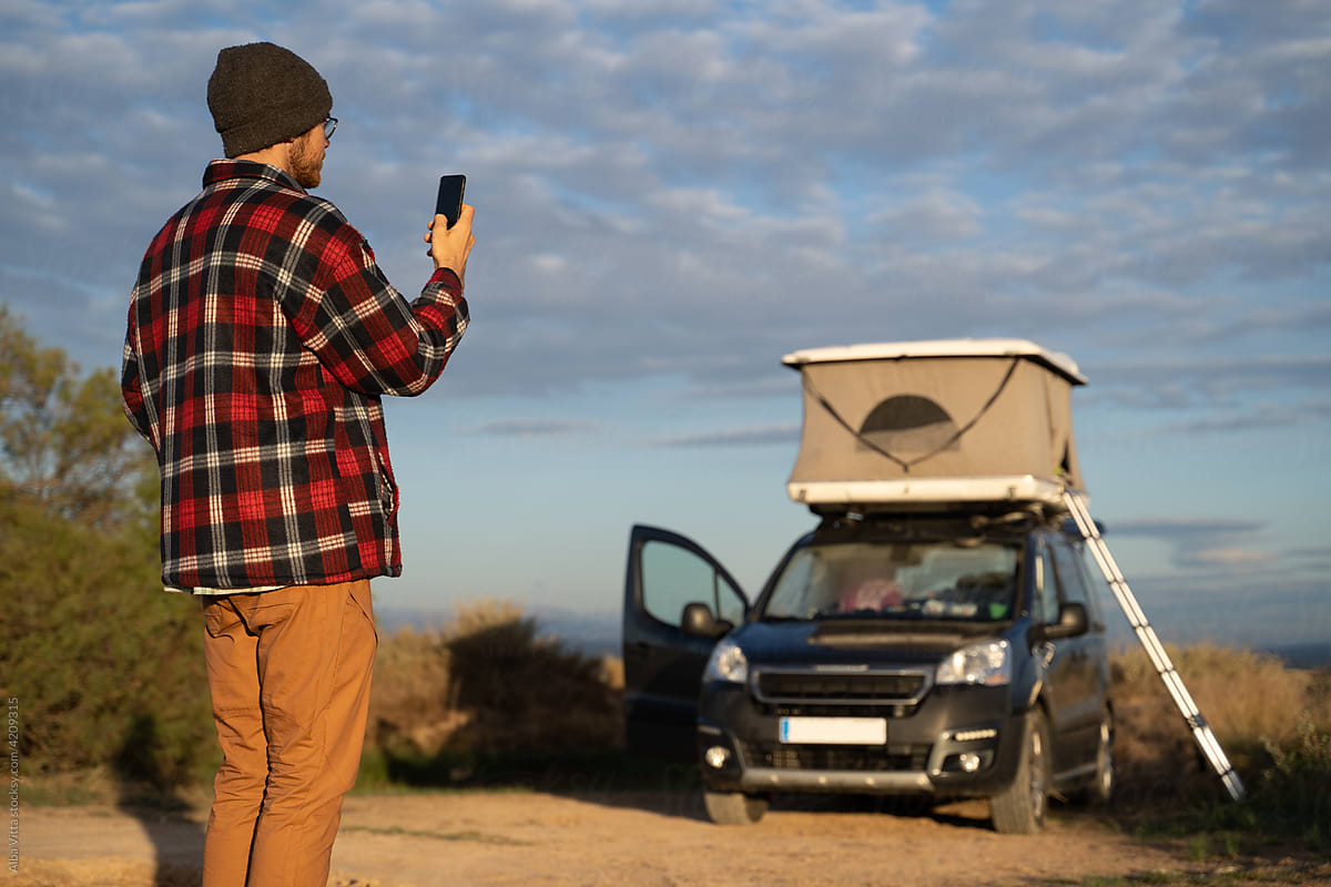 Man using phone in countryside next to camper van