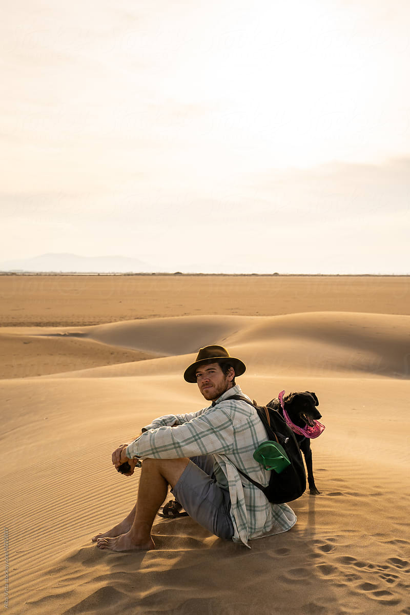Man sitting on top of dune in desert