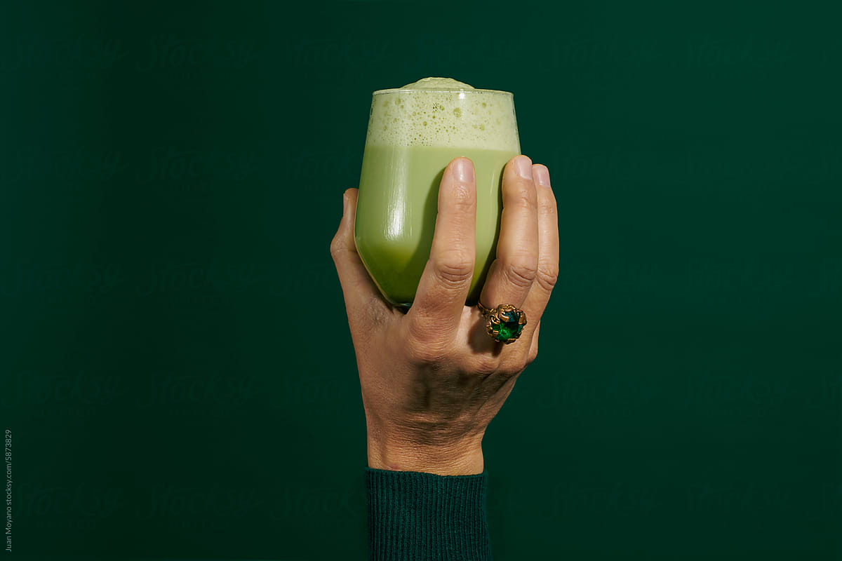 man holds a glass with iced matcha latte