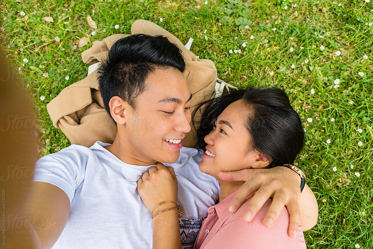Young Filipino Couple Taking A Selfie While Lying Down On Grass By