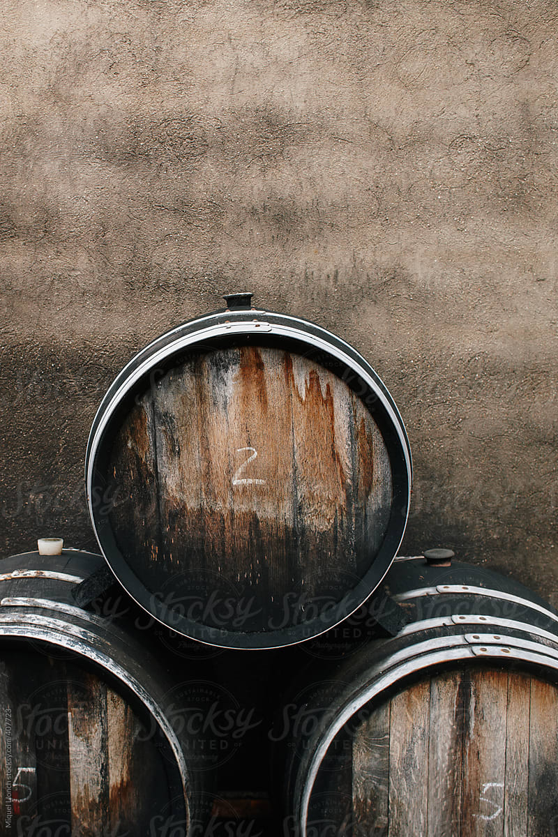 Close up of three aged wine barrels and concrete old and grey wall