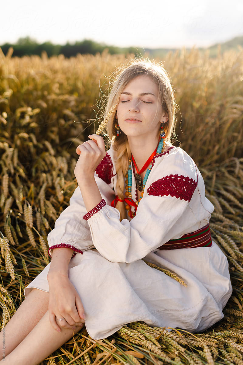 Girl in Ukrainian wear resting among wheat field