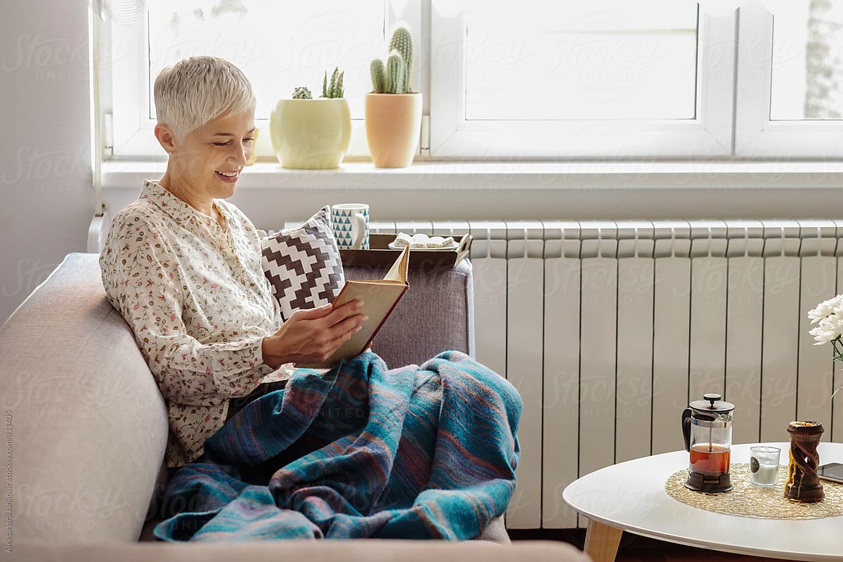 Senior Woman Relaxing At Home And Reading A Book
