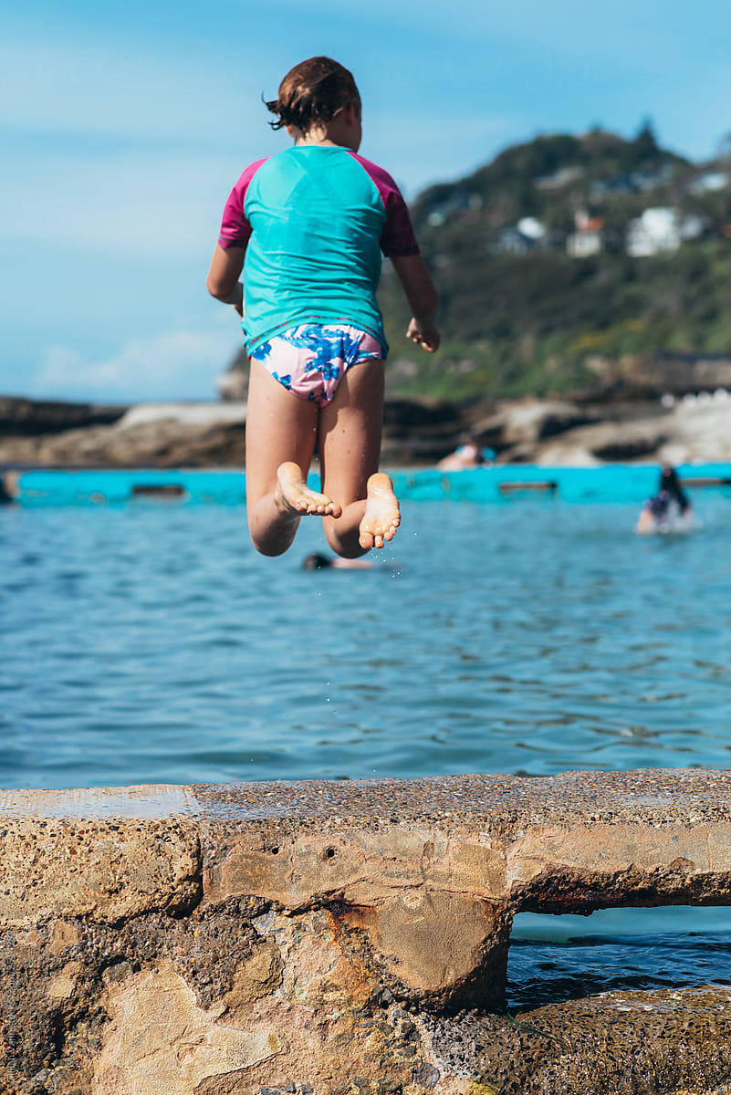 girl jumping into ocean pool