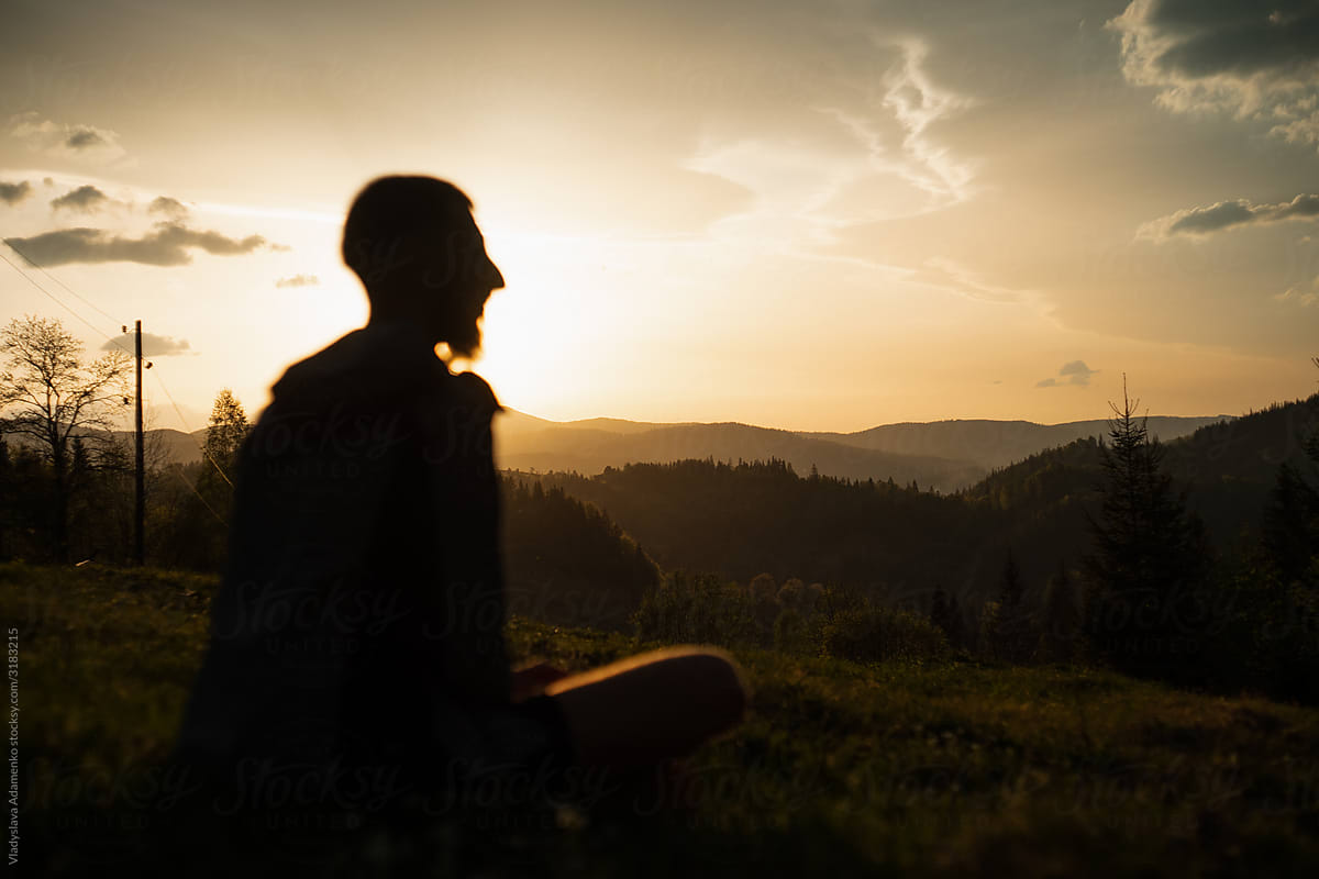 Man sitting at the dramatic sunset in the mountains