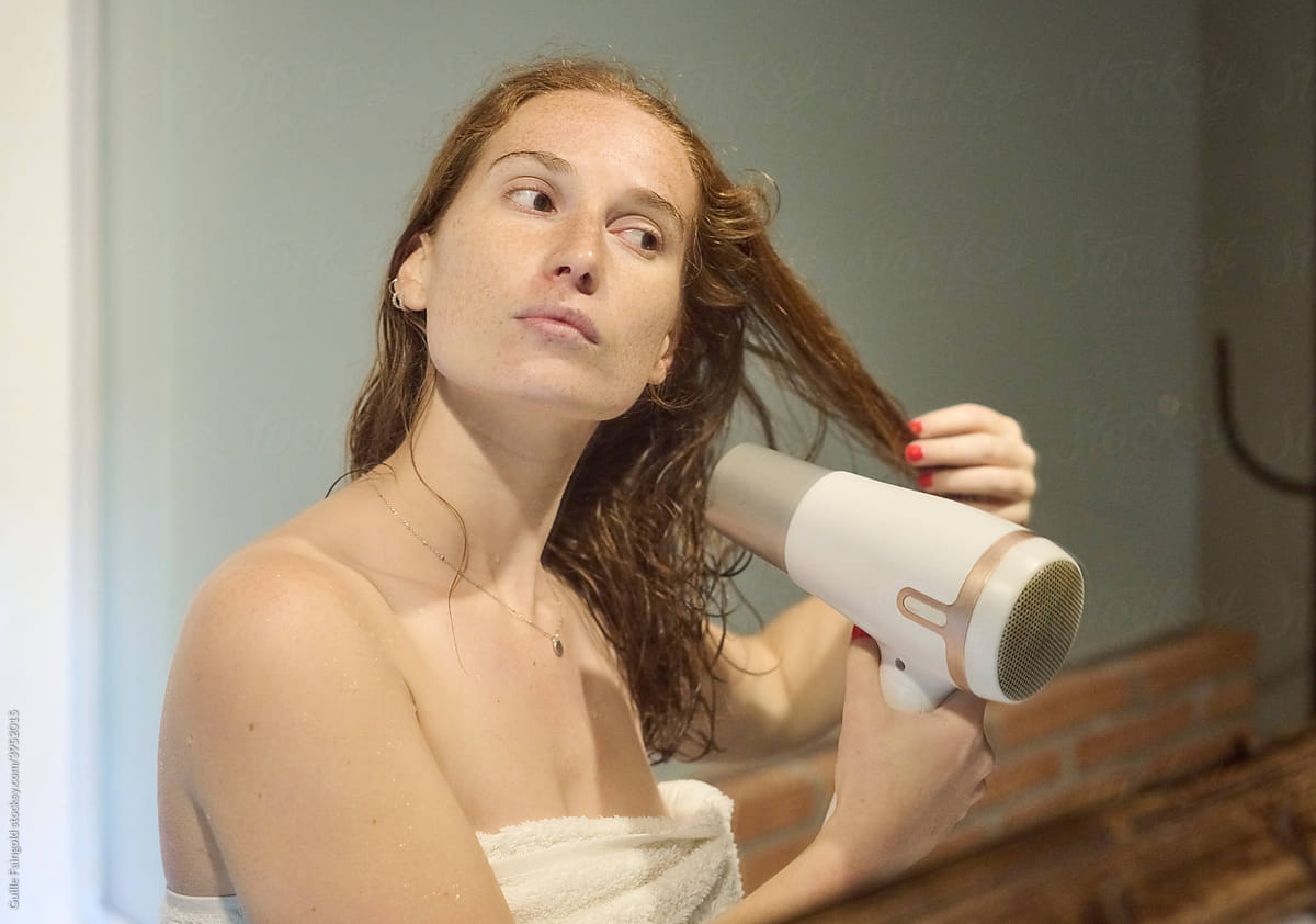 Ginger woman blow drying hair