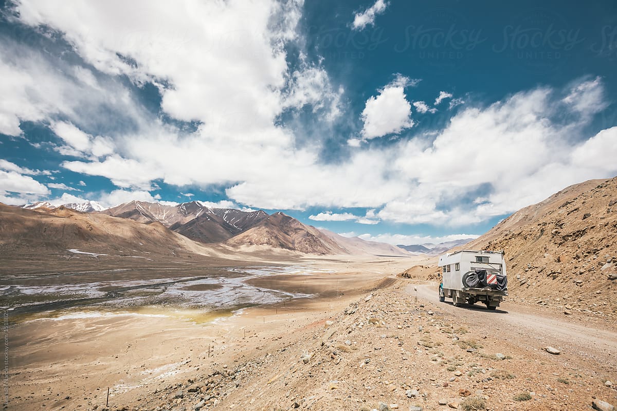 camping truck in rugged mountain landscape on the pamir highway - tajikistan