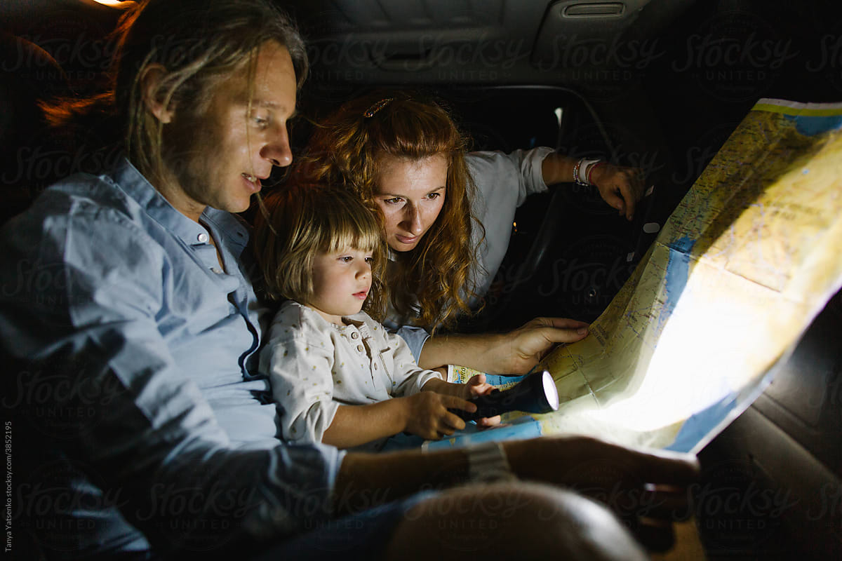 A family of three with a map in a car