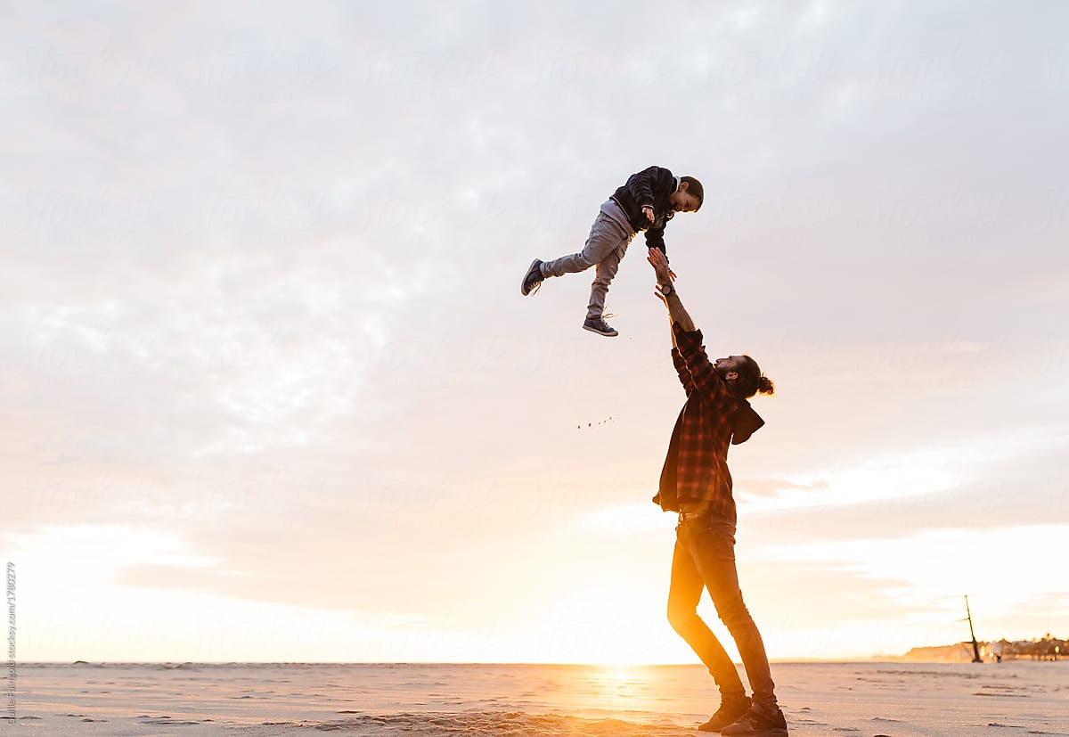 Man lifting son in sunset