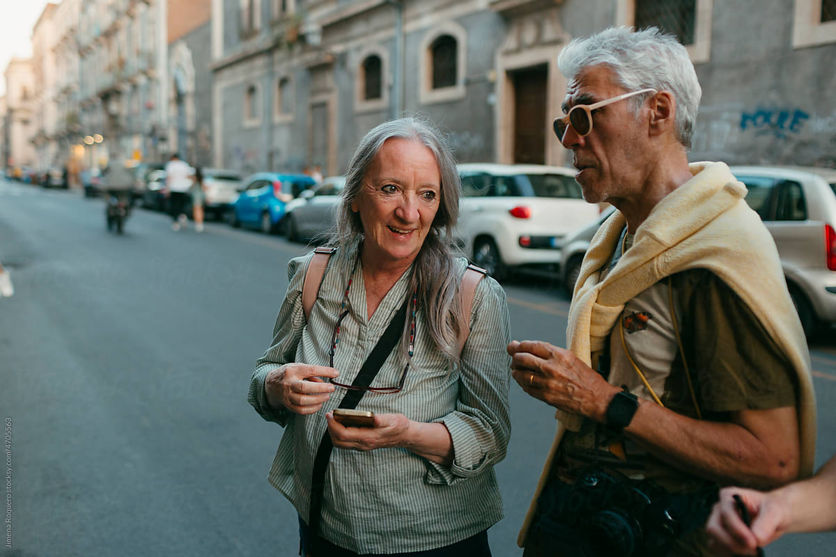 Senior tourist couple chatting in old Italian city street