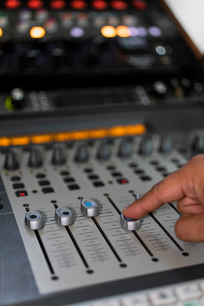 Male hand moving buttons from an audio console with one finger