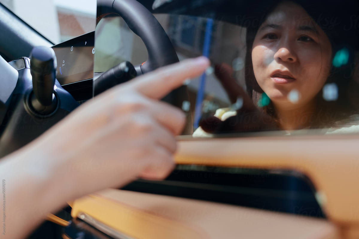woman driver touches control screen in modern electric car