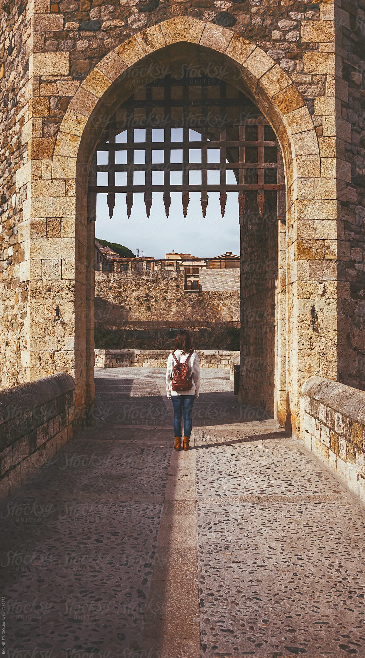 Back view of woman standing on the medieval bridge of Besalu. Girona, Spain.