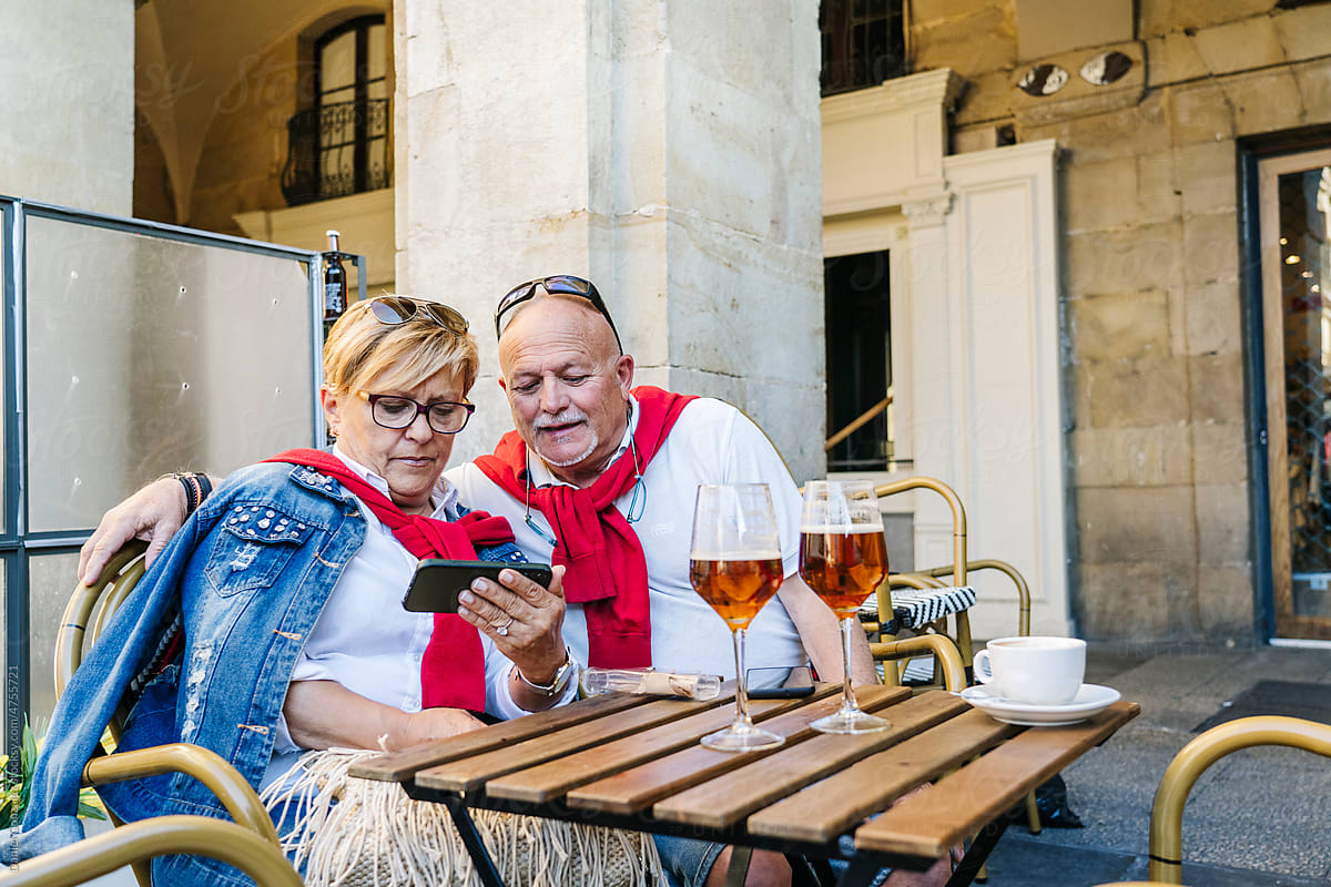 Elderly couple watching video in outdoor cafe