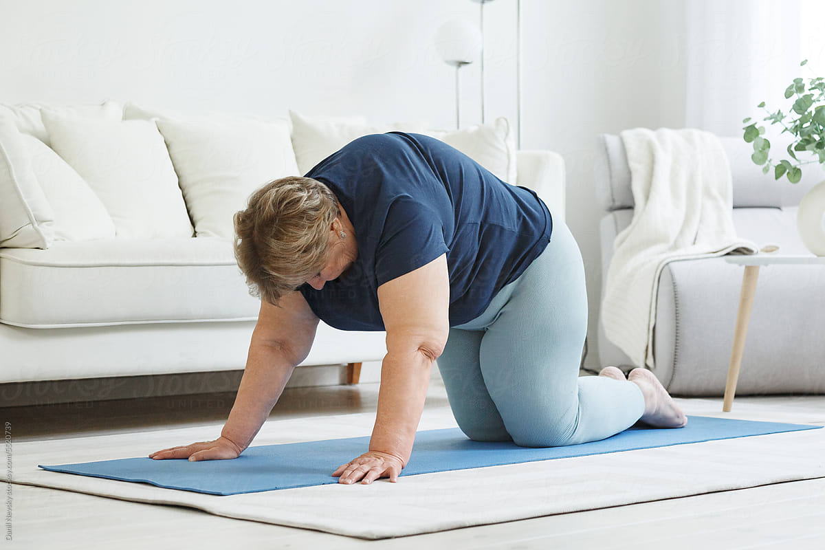 Plus Size Woman Doing Cat Pose On Mat by Stocksy Contributor