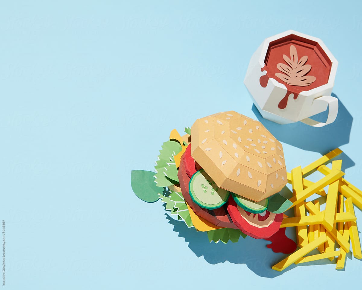 Paper craft burger with cup of coffee and french fries on a blue background.