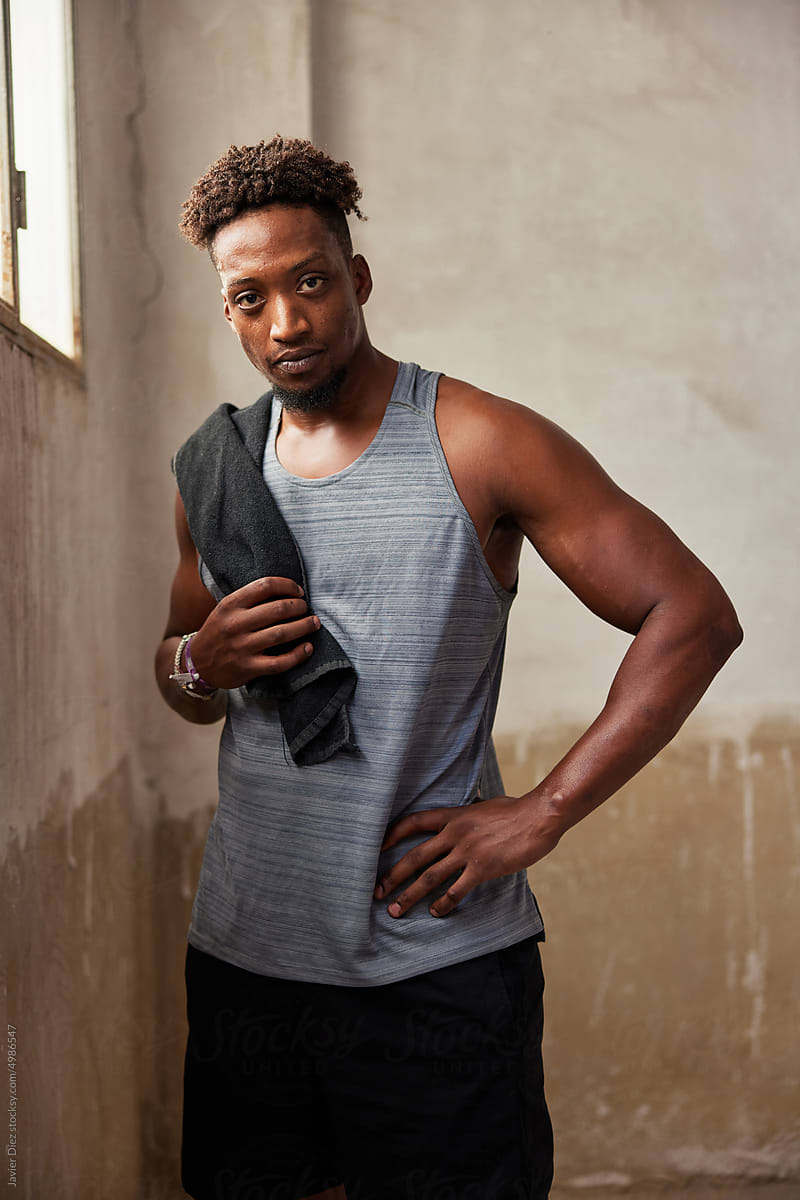Confident black athletic guy standing in shabby gym
