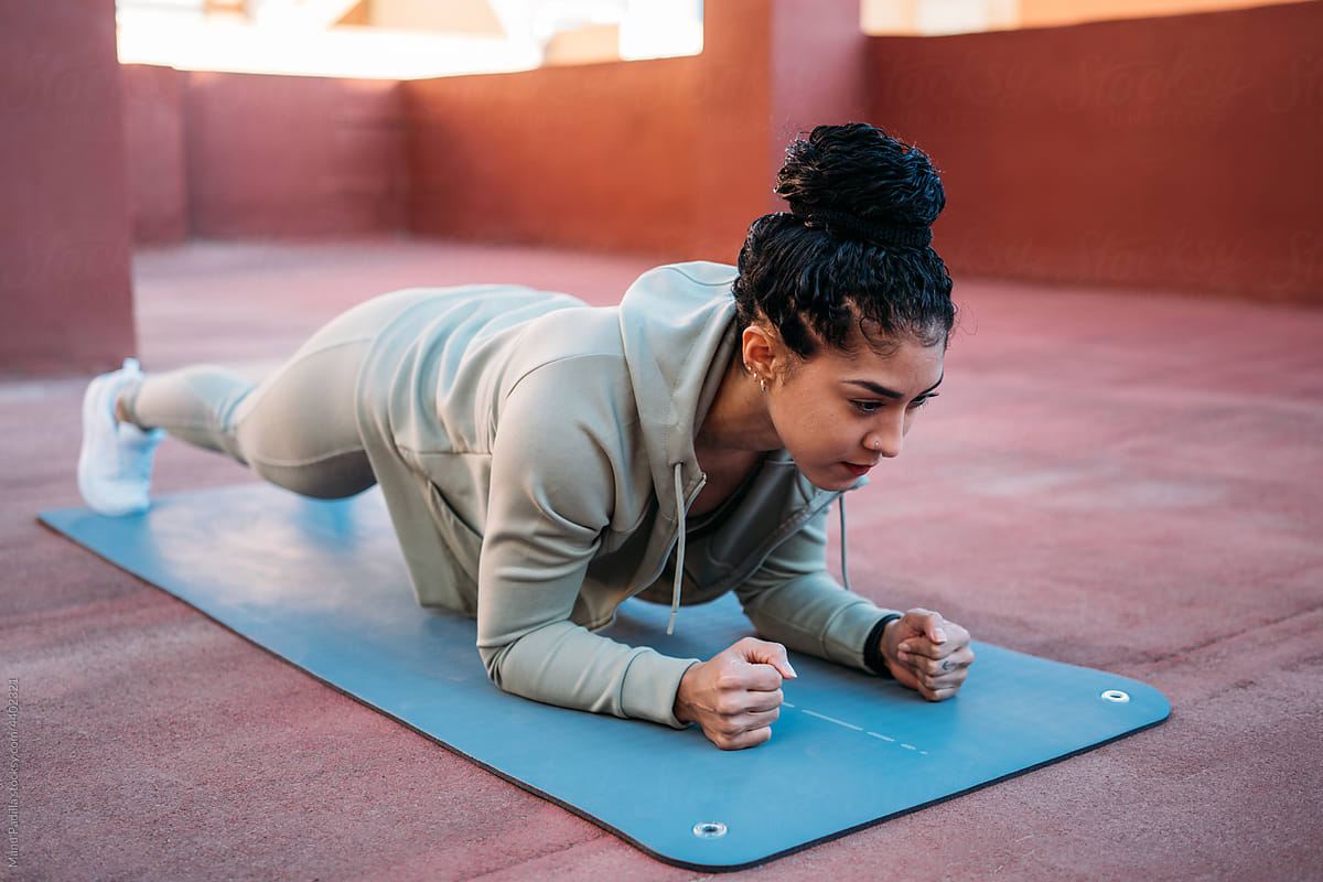 Dark haired woman doing plank exercise on mat