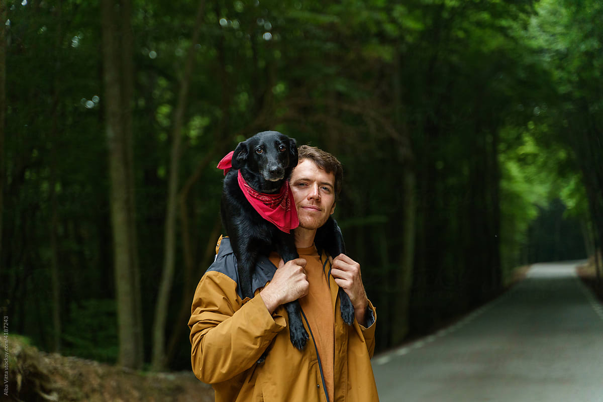 Portrait of happy man and dog walking in the middle of road in forest