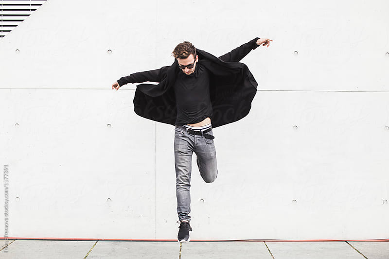 Man in black jumping in front of the concrete wall