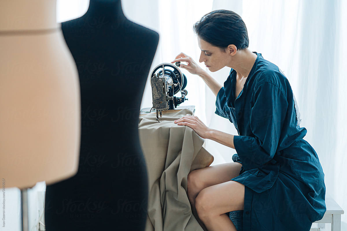 Female designer sewing on machine in workshop